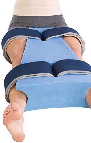 Equipment for Sleeping After Hip Replacement - A person's legs with hip abductor pillow strapped between while sitting up