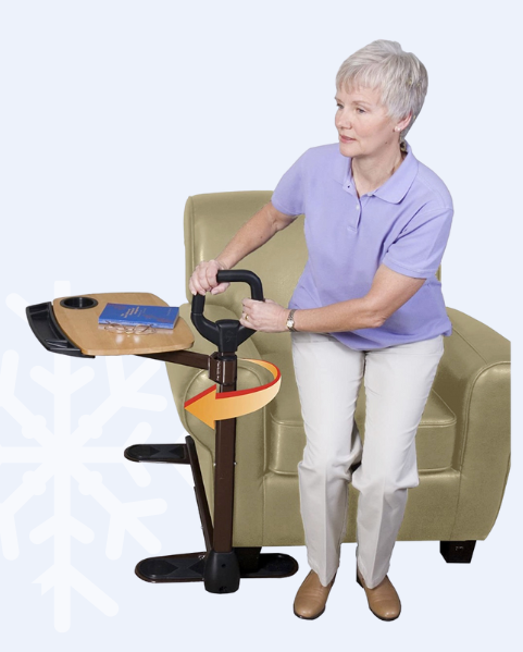 A woman is coming to a stand using a handle attached to a swiveling tray supported under the side of a chair.