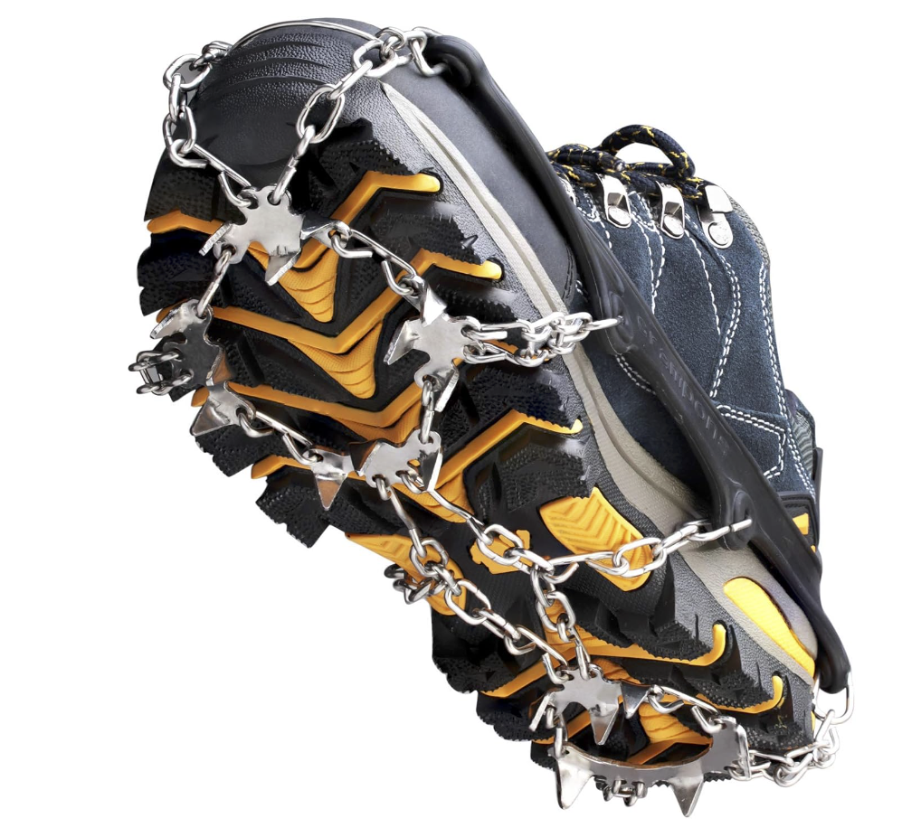 An image displaying a close-up view of a heavy-duty hiking boot wrapped in metallic crampons. The crampons feature sharp, pointed spikes and chain links designed to provide traction on ice. The boot is predominantly navy blue with yellow and black accents. The crampons are attached over the boot's sole and around its contours, with some spikes prominently visible at the front, indicating their use for ice climbing or walking on slippery surfaces. How to Avoid Slips and Falls on Ice: Essential Winter Safety Tips